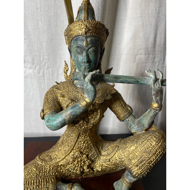 Lovely bronze-like metal seated Asian sculpture (likely Tibetan) lamp. The figure is seated, playing a flute, and wearing...