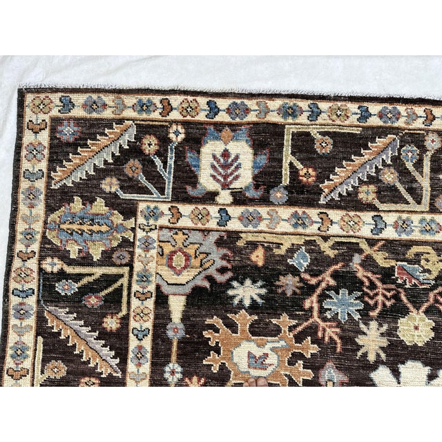 An allover Oushak-design carpet on a deep brown-black field, with the open drawing and large, spaced motifs the style is...