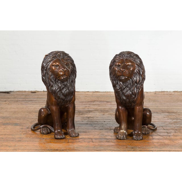 A pair of contemporary cast bronze outdoor lions with dark bronze patina. Created with the traditional technique of the...