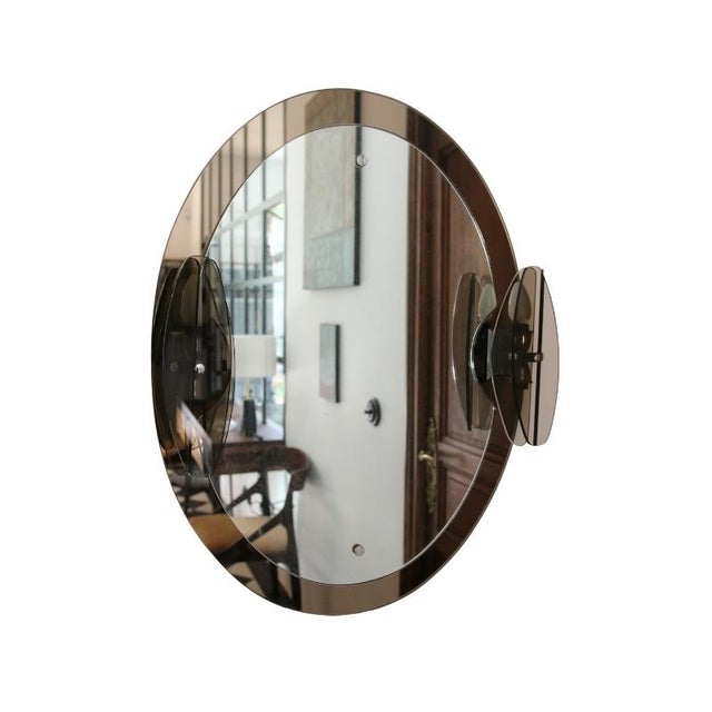 Mirror from the 1970s, attributed to Italian designer Antonio Lupi for Cristal Luxor. Oval mirror mounted on a smoked...