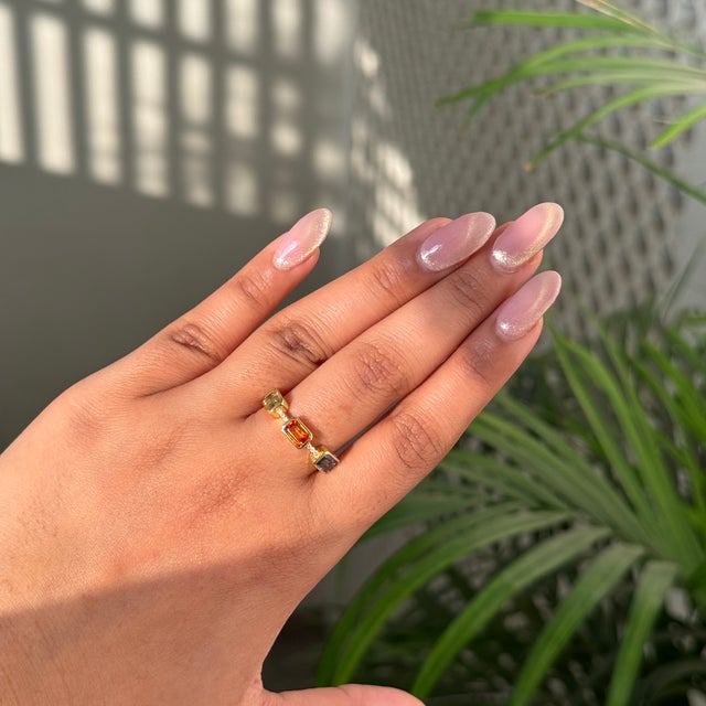 This three-stone ring featuring a 1.92 carat emerald cut multi sapphire, set in 14k yellow gold. The sapphire measures...