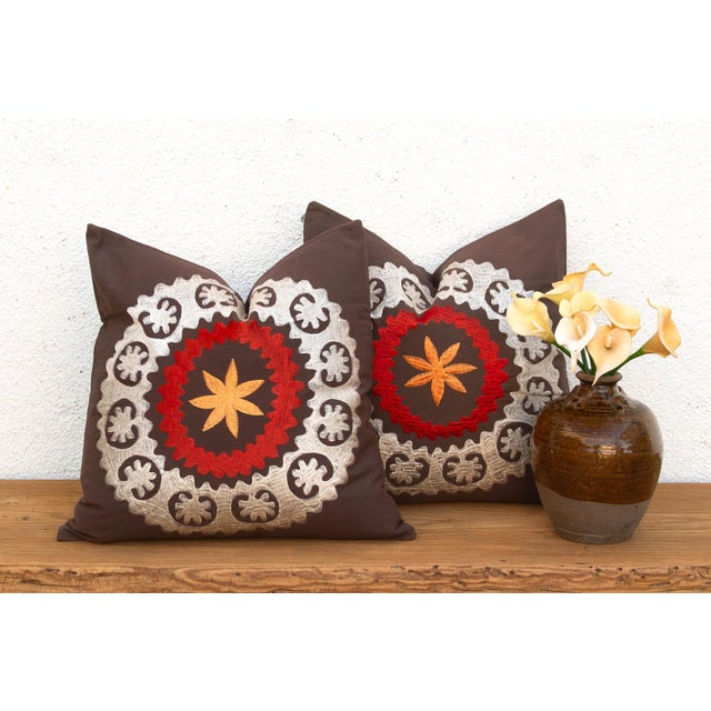 A radiant orange-gold starburst sits at the center of each pillow in this well-matched pair, ringed first in red and then...