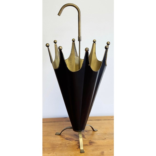 Vintage footed metal umbrella motif stand with exaggerated handle. Features upside down painted black umbrella with gold...