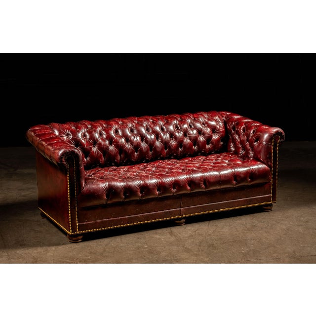 Antique leather sofa in a rich oxblood on turned, round oak feet. This item features leather nail heads within the tufts...
