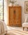 A tall, slim cabinet in honey-amber wood, dressed throughout in the look of bamboo: the frame, rails and legs are turned...