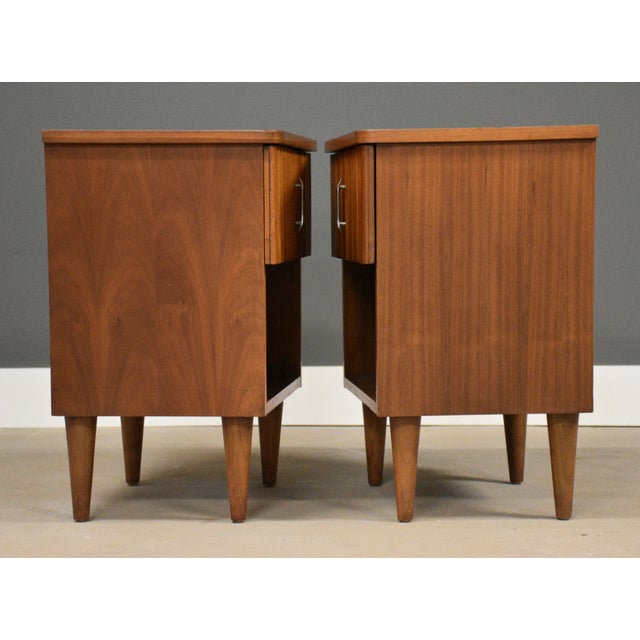 A pair of mid century modern walnut single drawer nightstands with sculpted fronts made by Young Manufacturing. Circa...