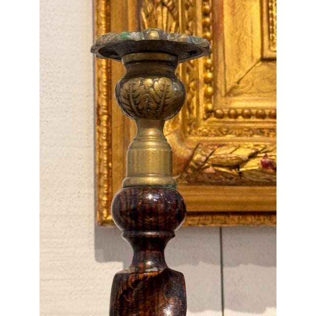 A pair of oak barley twist candlesticks with brass sconces and turned dished bases.