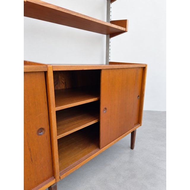 An iconic two-span modular wall unit in fine teak, dating from the 1960s. This splendid example of mid-century...