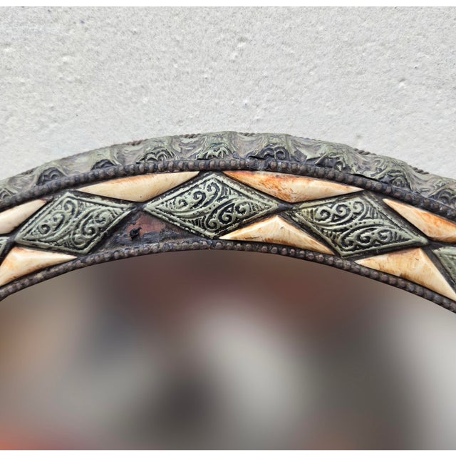 Handcrafted Moroccan round mirror featuring a metal frame inlaid with resin. The piece shows beautiful organic variations...
