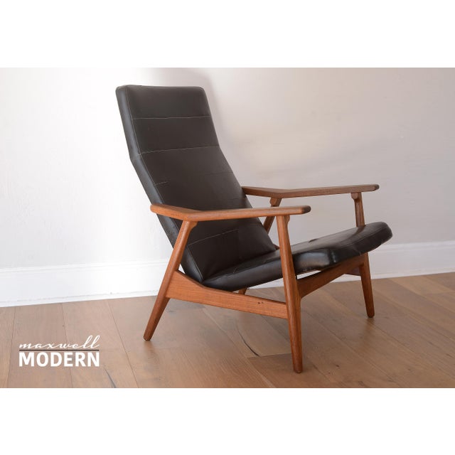 Handsome vintage mid century modern reclining lounge chair with teak wood and black vinyl. Upholstery shows parallel...