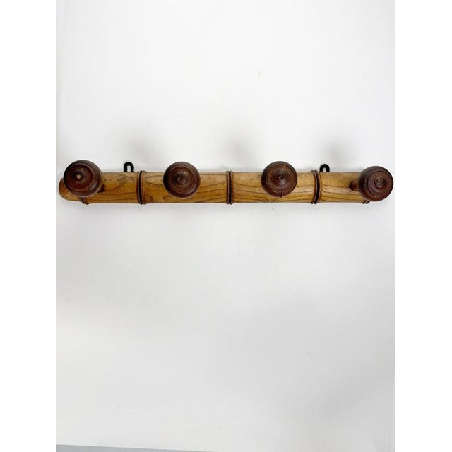 French wooden wall-mounted coat rack dating from the 1960s. The elongated structure features a warm-toned wooden rail with...