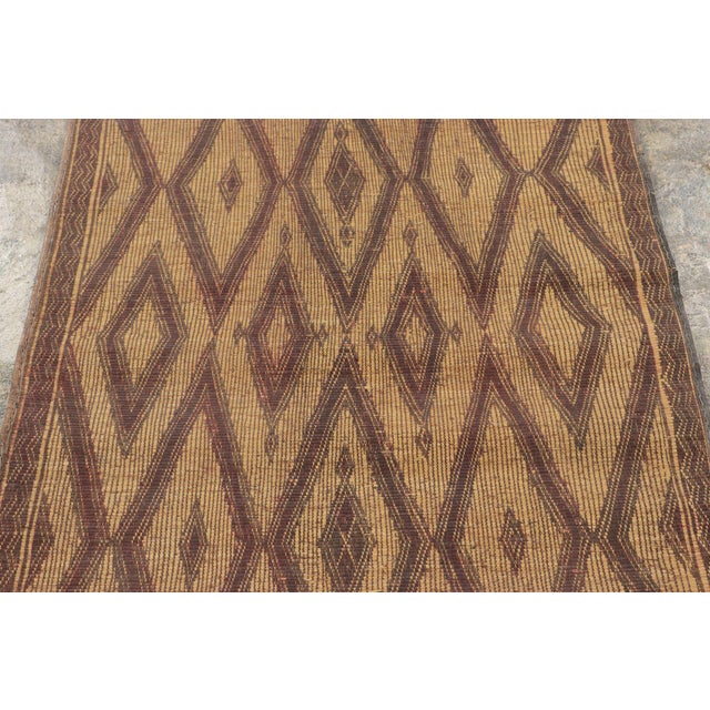 Made with handwoven reed and camel leather in Mauritania circa 1950-1960, this 3x5 vintage Tuareg mat is an exceptional...