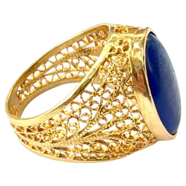 Vintage 18K yellow Gold Filigree Oval Lapis Ring. Ring centers on a substantial oval lapis lazuli stone, bezel set within...