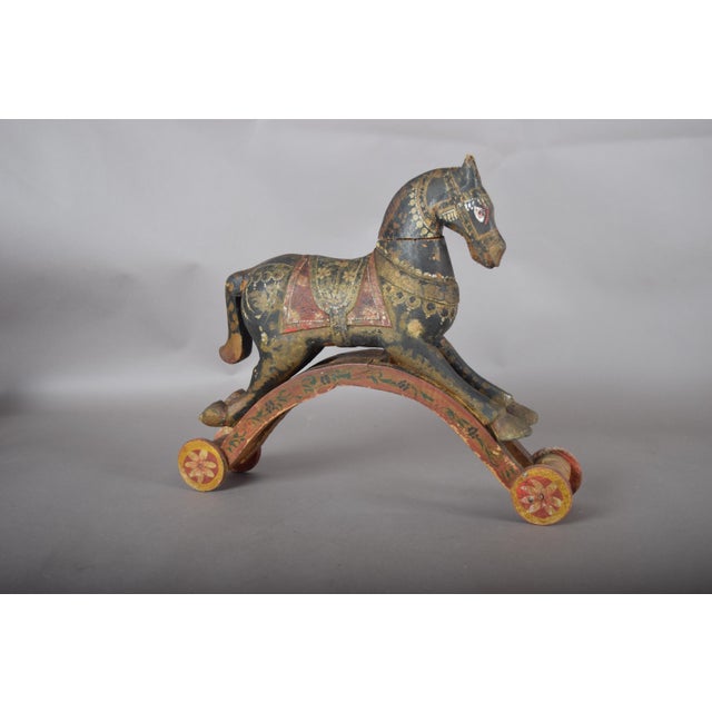 Antique Indian folk-art horse, hand-carved in wood with an aged painted finish in black, red and gold tones. The standing...