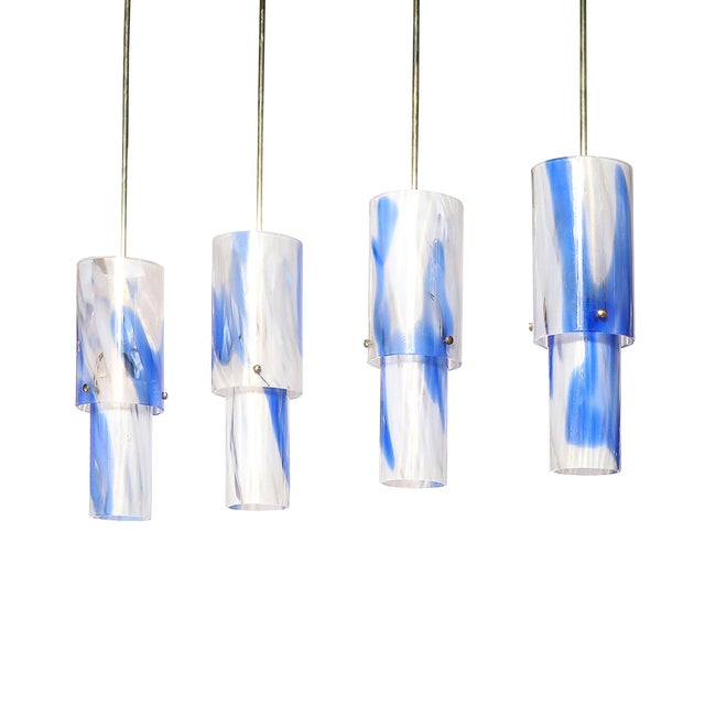 A set of four Mid-Century Modernist cylindrical pendant chandeliers, crafted from hand-blown Murano blue and white glass,...