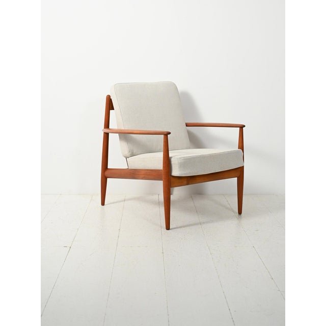 An elegant Danish teak armchair from the 1960s, an expression of Grete Jalk's organic modernism, with an original...