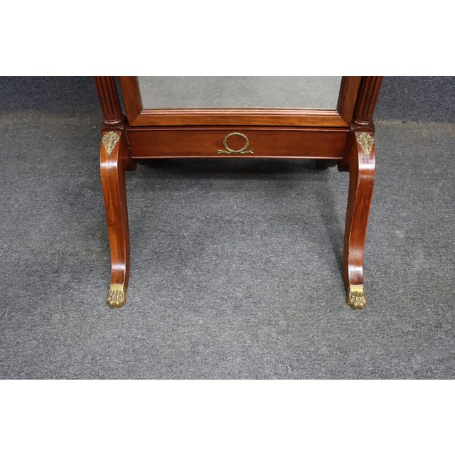 Edwardian style freestanding cheval dressing mirror crafted in mahogany with brass decorative accents and urn finials....