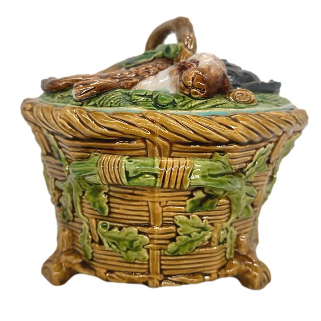A Minton Majolica Game Pie Tureen, Cover, and Liner, the base molded as a wicker basket with green glazed oak leaves and...
