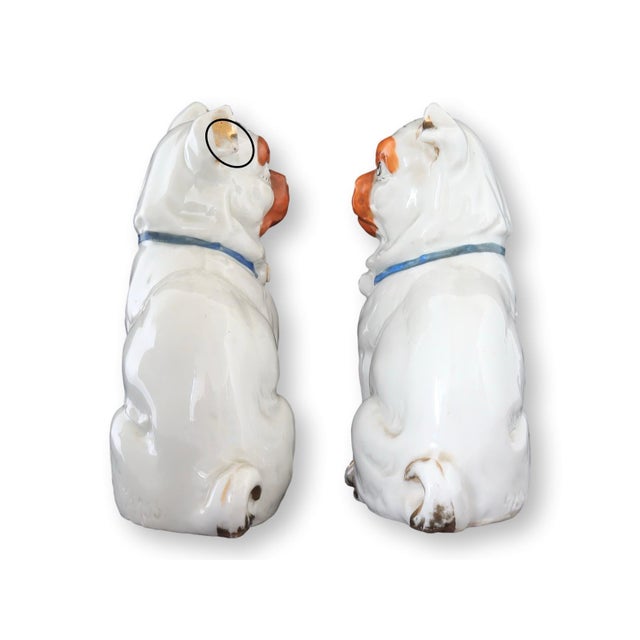 This charming pair of antique German porcelain pug figurines features expressive faces with hand-painted orange accents...