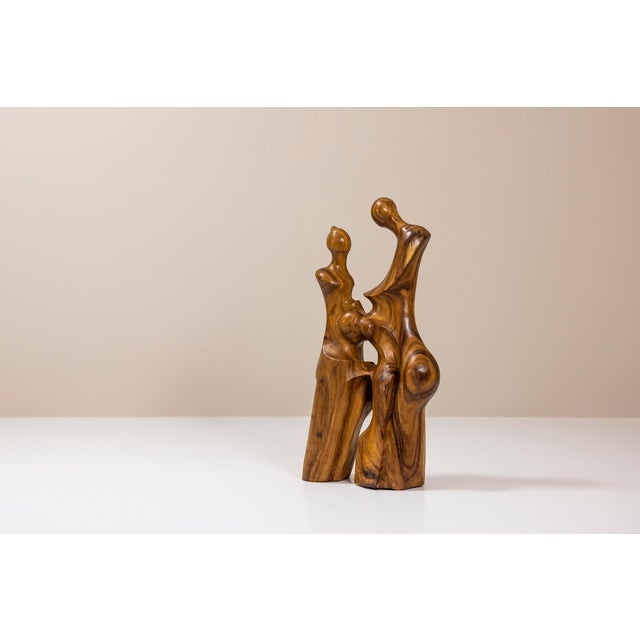 This Balinese biomorphic walnut sculpture features two abstract figures standing closely, carved with flowing lines and...