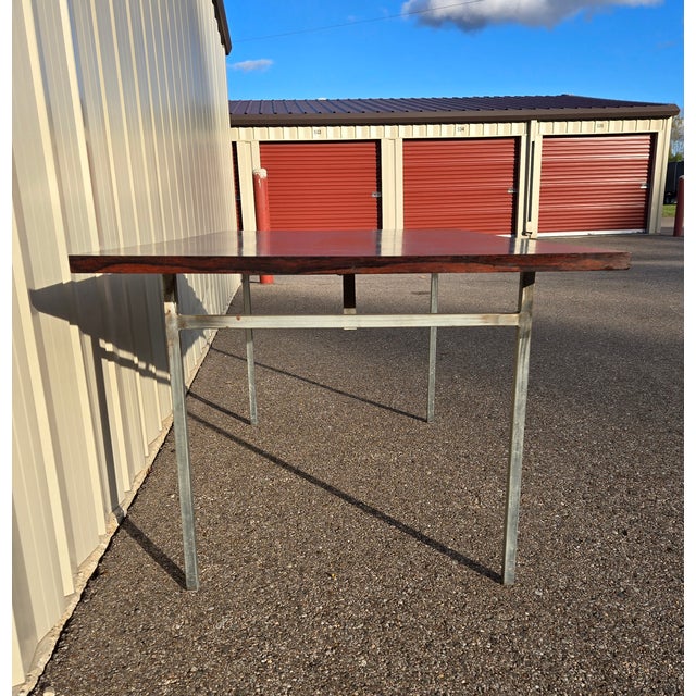 Vintage rosewood dining table on metal legs. I believe the legs are aluminum. The rosewood has a very deep color and some...