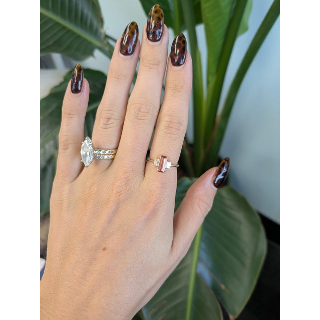 A 0.79-carat orange imperial topaz emerald-cut sits at the center of this solid 14K yellow gold ring, framed by two earth-...