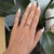 A rare padparadscha sapphire glows in a soft sunset blend of pink and orange at the center of this oval ring, accented...