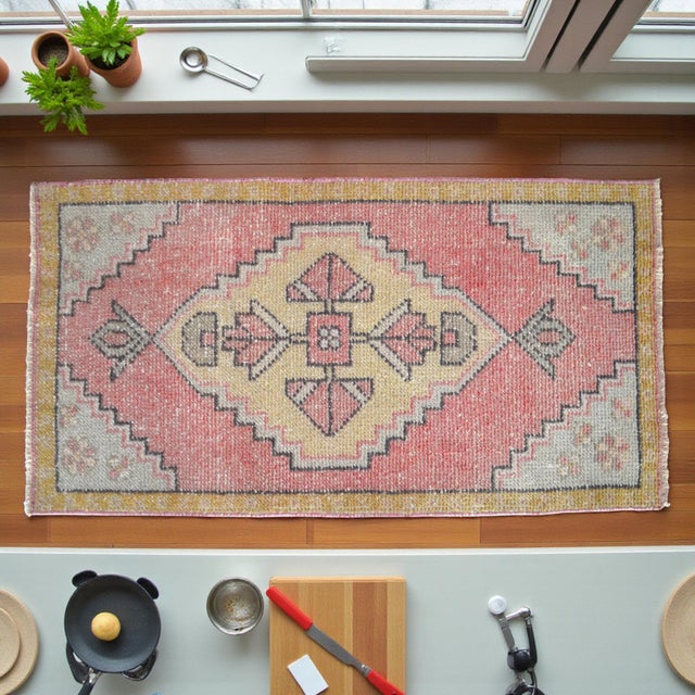 Authentic hand-knotted accent mat in soft sun-faded coral and pale yellow tones — perfect for entryways or bedside spaces....