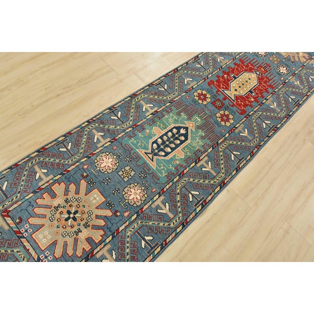 A tribal Caucasian Kazak runner hand-knotted with fine wool on a cotton foundation. This rug features a row of geometric...