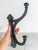 Large antique rustic cast iron double arm wall hook. No makers mark. Some oxidation. Hardware is not included.