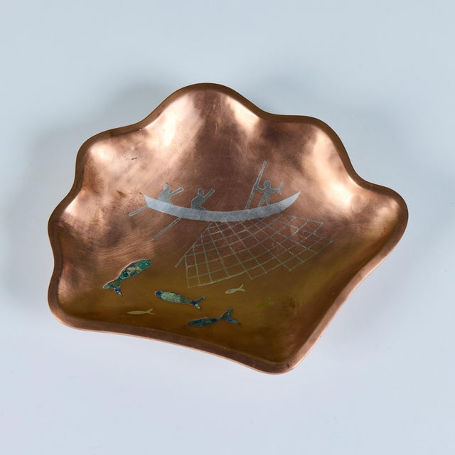 Mexican made dish, c.1960s, comprised of copper, brass and silver. It's freeform shape showcases a fishing scene with...