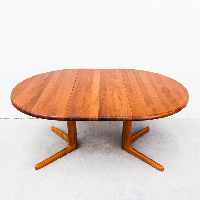 A solid teak split pedestal base dining table with two leaf extensions, made in Denmark by Juul Kristiansen in 1983. At...