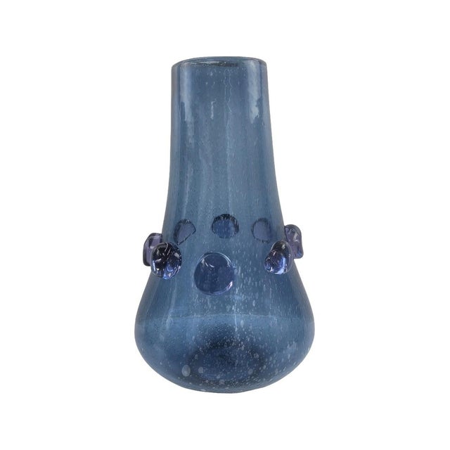 The softly tapered silhouette features a rich blue tone enhanced with delicate bubble detailing within the glass. Raised...