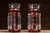 A striking pair of ruby red glass mantle lusters, each featuring hand-painted enamel floral decoration with gold...