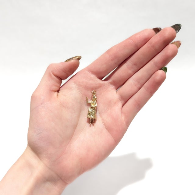 A fine vintage figural gold charm. In 14 karat yellow gold. In the form of a female hula dancer with a lei headband, lei...