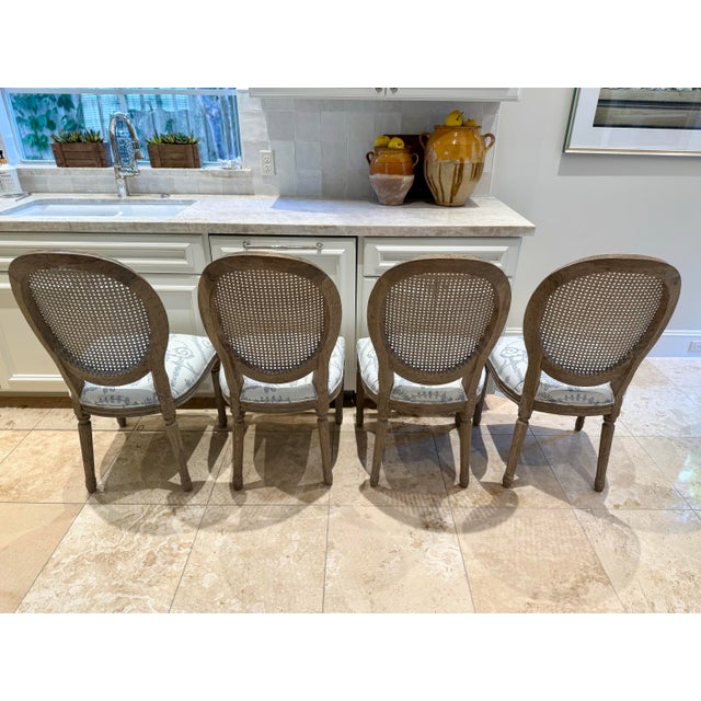 Set of four French styled dining chairs with oval cane backs. The chair seats are up upholstered in a lovely blue and...