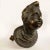 Bronze bust from the 17th century depicting a young boy with wavy hair and a robe gathered at the neck, ending in an oval...
