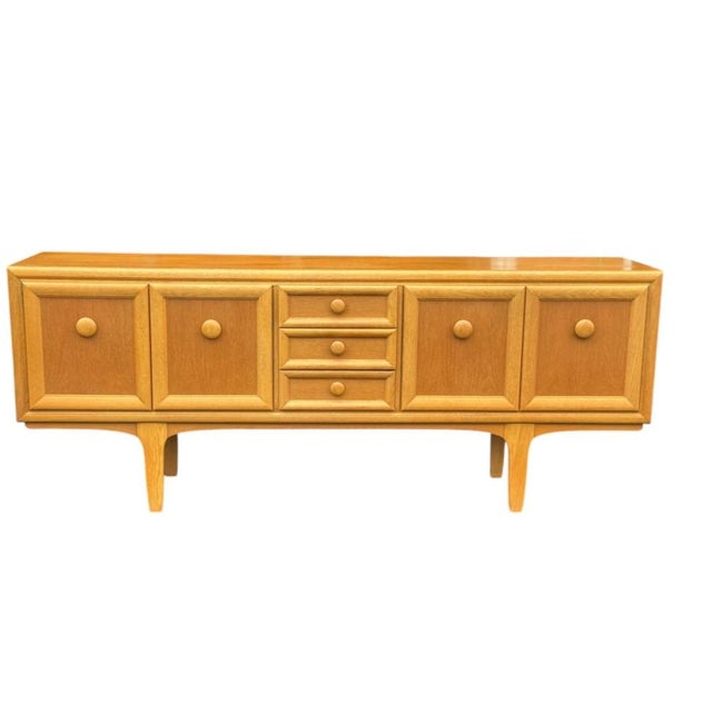 Architectural case with deeply framed panel doors. Integrated round pulls in solid wood. Three graduated center drawers....