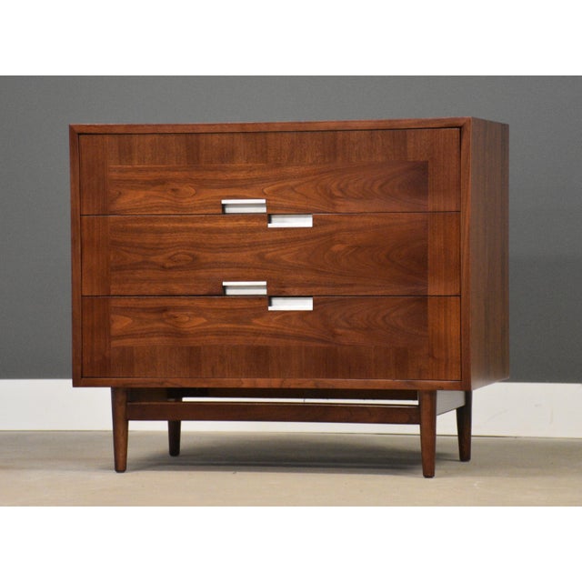 A mid century modern walnut three drawer dresser with aluminum x inlay and aluminum drawer pulls made by American of...