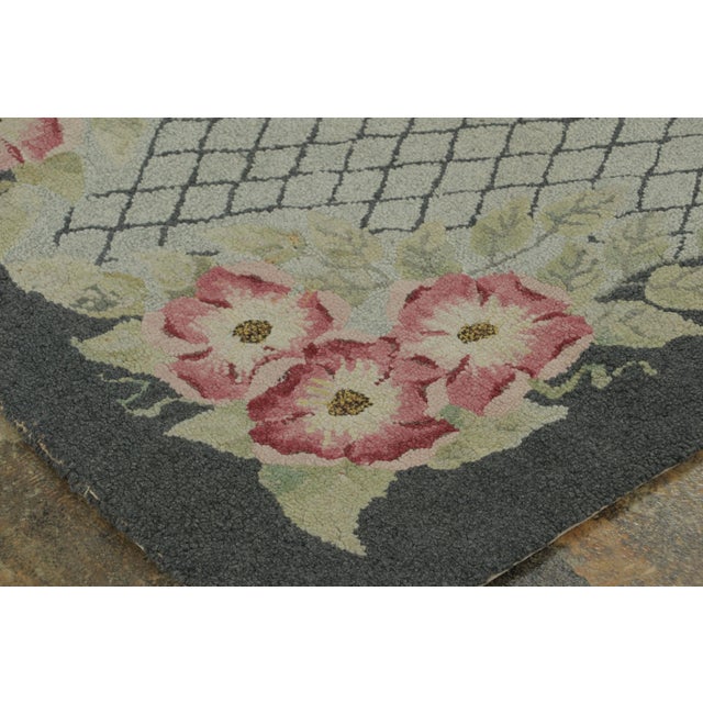 This antique 3x4 hooked rug, circa 1920–1929, features a floral trellis medallion framed by pink blossoms and scrolling...