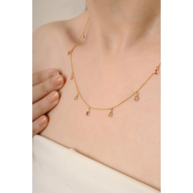 This elegant drop necklace features 1.37 carats of pear cut pink sapphires, each bezel set in radiant 14k yellow gold. The...