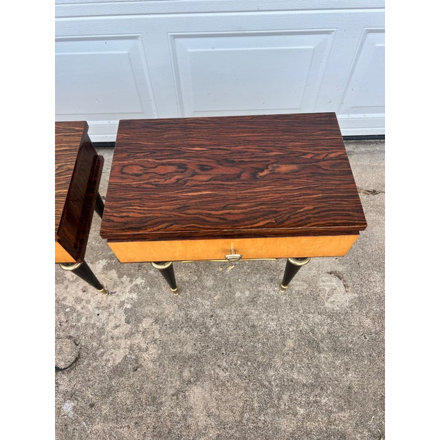 Elegant pair of Mid-Century Modern nightstands featuring beautifully figured wood veneers with contrasting light wood...