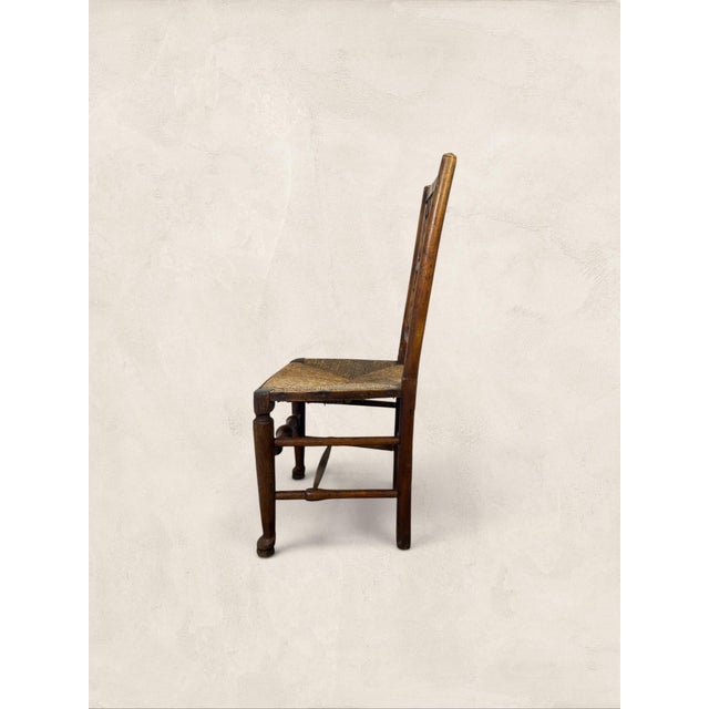 Antique English Ash Lancashire Spindle Back Chair with Rush Seat Settle into over a century of honest craftsmanship with...