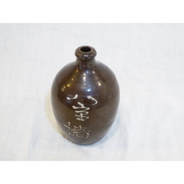 This glazed ceramic Japanese sake bottle with calligraphy is hand made.