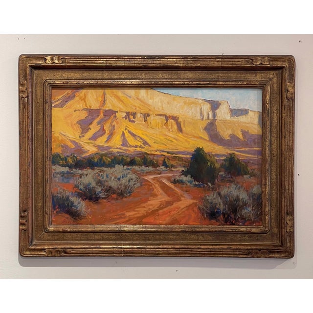 Road to Castle Valley captures a winding dirt path leading through a vibrant landscape, where golden hues of sunlight...