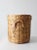 A lidded wicker basket with a rounded silhouette and softly flared rim, woven in a tight, even pattern with a warm natural...