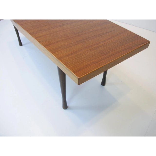 This boat-shaped coffee table with brown stained drumstick legs was manufactured in the 1950s. It is made of walnut and...