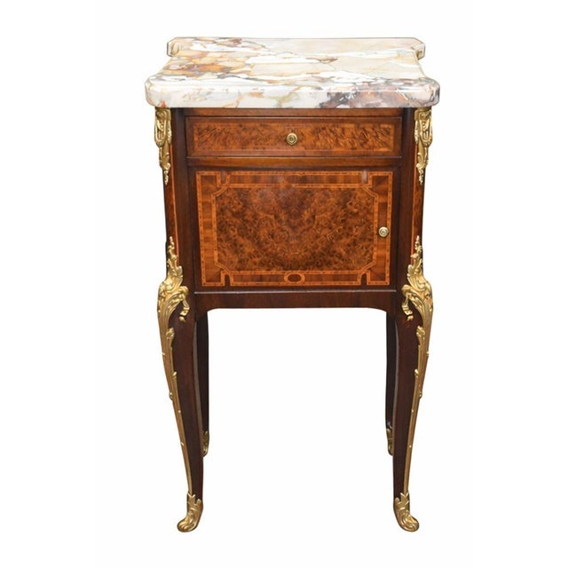 An elegant pair of French Louis XV-style nightstands crafted in the late 19th century, richly mounted in gilt bronze and...