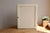 Ivory-painted wooden wall-mounted medicine cabinet with a simple and functional design. The interior features two glass...