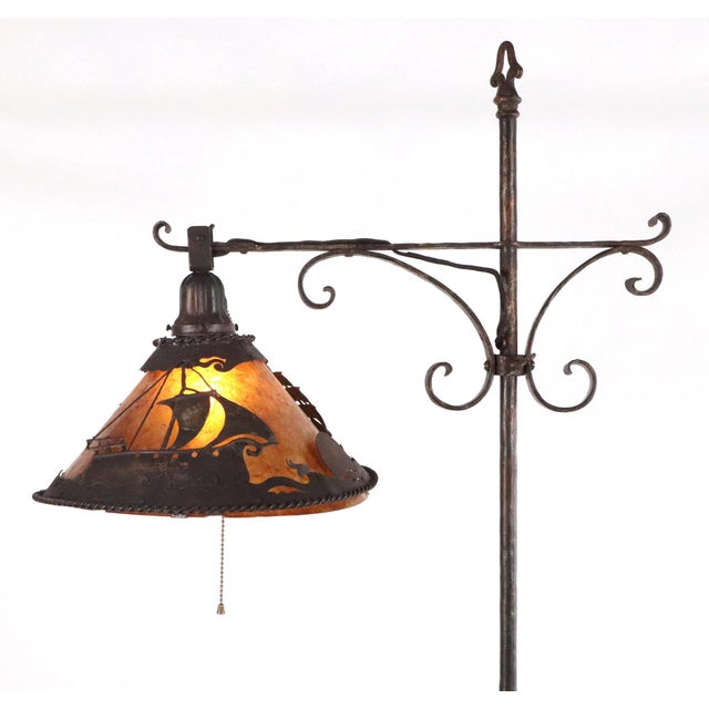 Arts & Crafts wrought iron floor lamp featuring a mica lampshade with ship motif overlays. The metalworking on the stand...